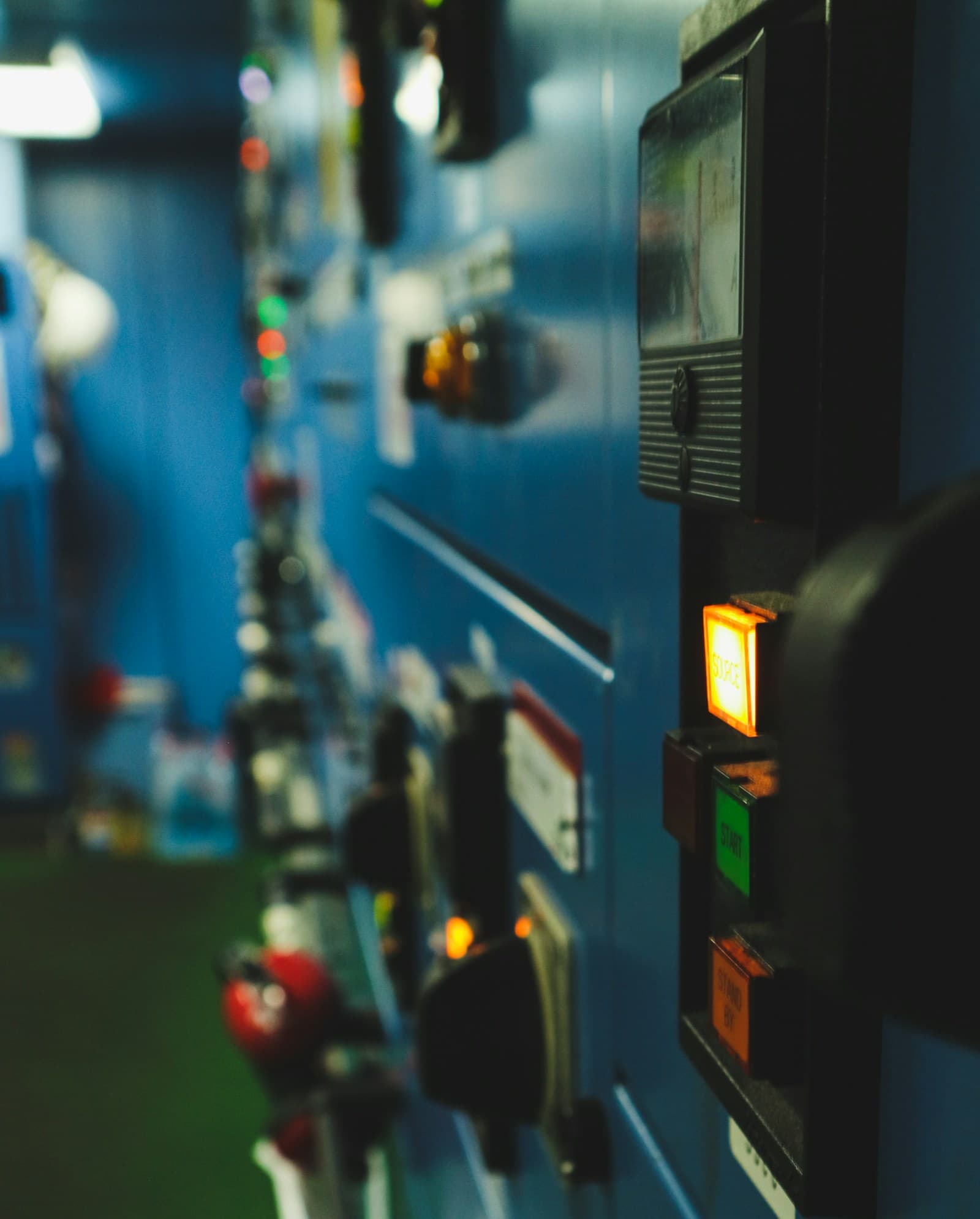 Ship monitoring panel with indicator lights and instrumentation in an engine room.